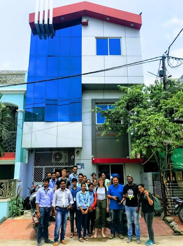 A group standing outside a blue-and-white office building.